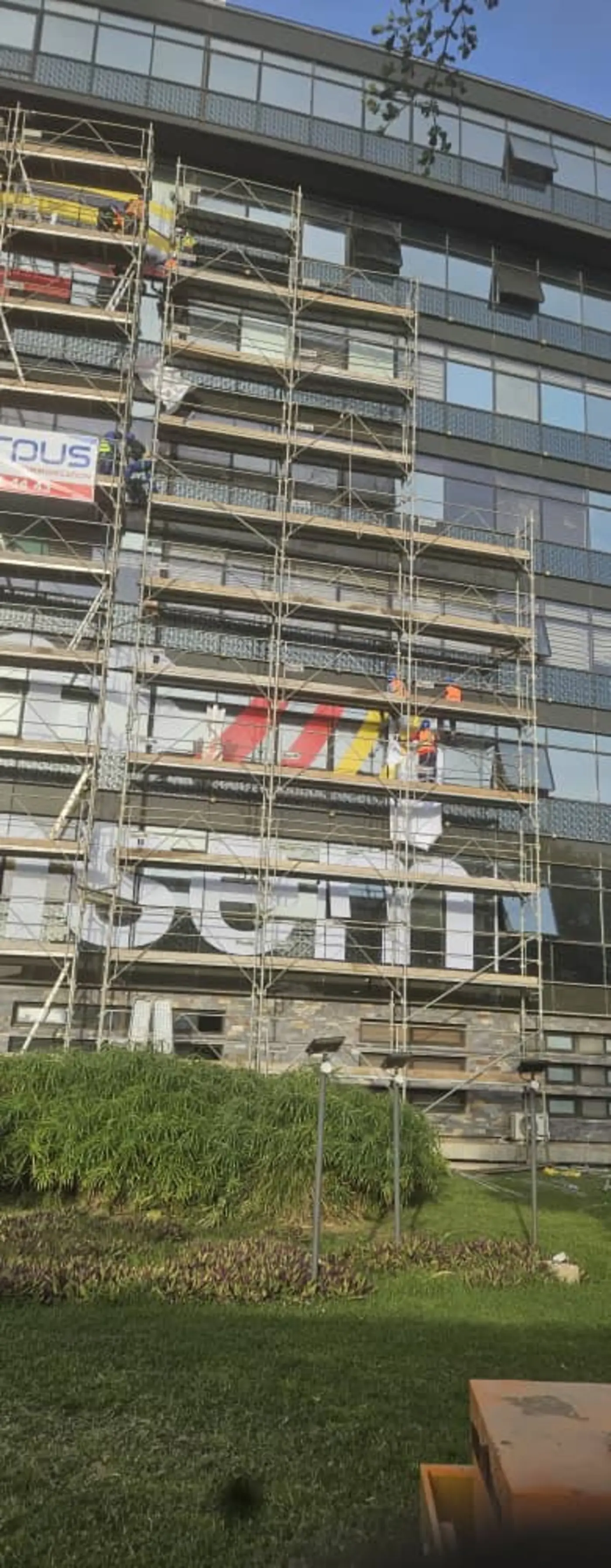 Équipes Caliha posant une signalétique depuis l'échafaudage d'une façade vitrée